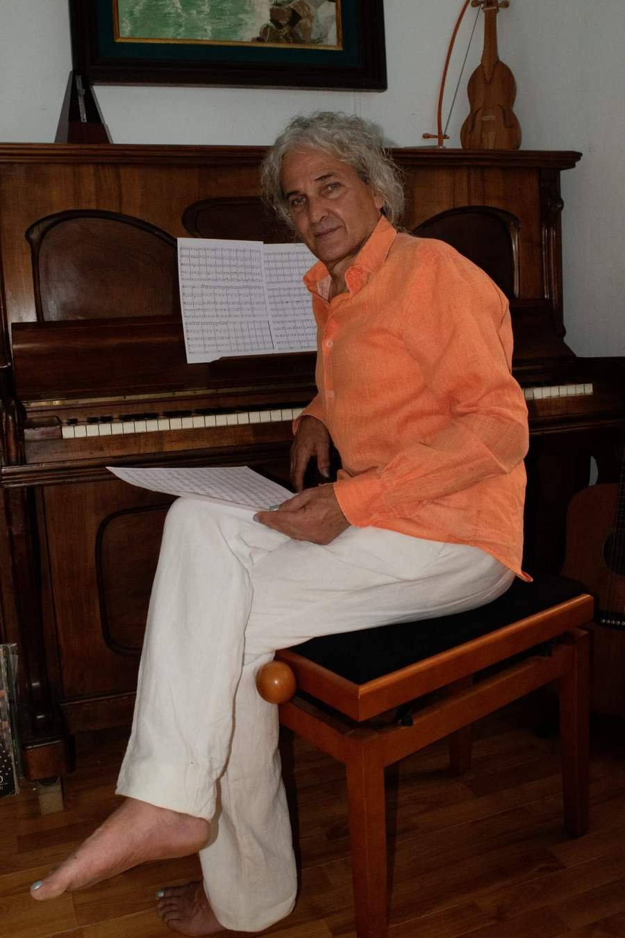 Álvaro Fernández Gaviria tocando guitarra y armónica a la vez en su estudio · 2023
